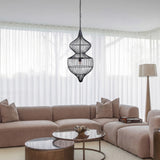 Libra Interiors Wire Cage Double Tiered Pendant Light in black steel hangs above a beige sectional sofa and round coffee tables in a bright living room.