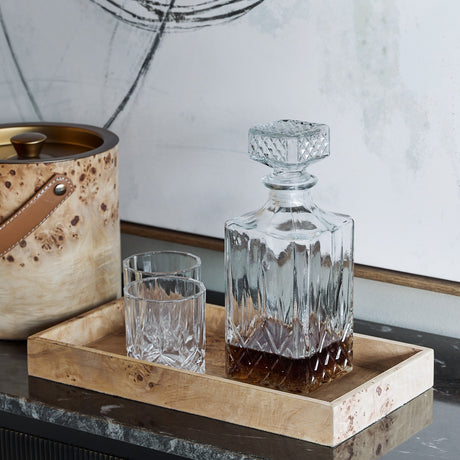 Libra Interiors Burlwood rectangular wooden serving tray in natural finish, holding a cut-glass whisky decanter and two tumblers on a dark console.