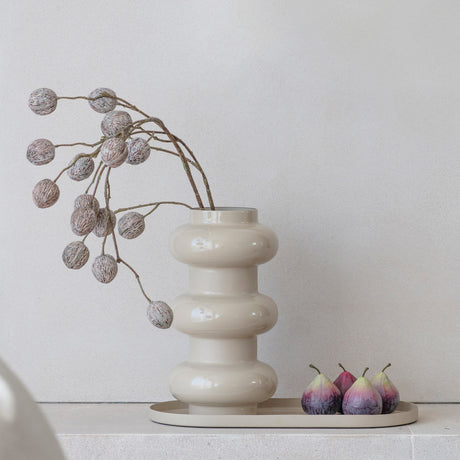 Libra Interiors Oval Gloss Enamel Serving Tray in cream holding four figs beside a cream bubble-form vase with a berry stem, on a pale stone surface.