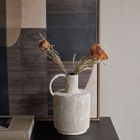 Libra Interiors Textured Cross-Hatch Handle Vase in cream holding dried banksia and grasses, styled on a dark console beside an abstract framed artwork.