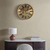 Libra Interiors Moving Cogs World Map wall clock in antique gold hung above a marble-topped console with a wooden lamp and books.