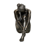 Libra Interiors textured resin seated female sculpture in antique gold, head resting on bent knees with one leg extended, on a plain white background.