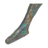 Close-up of the Libra Interiors Verdigris Seated Reading Man resin sculpture's lower leg and foot, showing rough cast antique gold and blue patina texture.