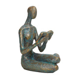 Libra Interiors Reading Woman resin sculpture in antique gold verdigris finish, seated cross-legged with an open book, shown on a plain white background.