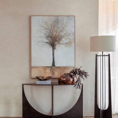 Libra Interiors Sculpted Glass & Iron Console Table in black with arched intersecting base and smoked glass top, styled with a vase and framed tree artwork.