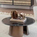 Libra Interiors Round Black Marble Smoked Gold Coffee Table styled with a book and bronze sculptural decor in a living room with a cream rug.