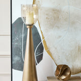 Libra Interiors Tapered Iron Hammered Glass Floor Lantern in gold with copper lustre glass vessel, styled beside abstract artwork in a contemporary living room.