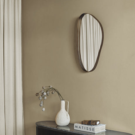 Libra Interiors Corrugated Asymmetric Wall Mirror in grey with ribbed metal frame, hung above a marble console with a vase and books.