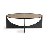 Libra Interiors Bronze Glass Sculptural Coffee Table in black, with an oval smoked glass top on intersecting curved iron panels, on a white background.