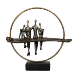 Libra Interiors Rough Cast Four Figure Circle Family Sculpture in antique gold bronze, four figures seated on a branch within a ring, on matt black base.