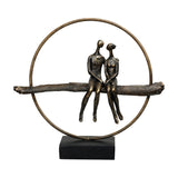 Libra Interiors Antique Gold Circle Seated Couple Sculpture with two resin figures on a textured branch within a metallic ring on a black base.