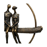 Libra Interiors Antique Gold Circle Seated Couple Sculpture close-up showing two stylised resin figures with rough cast bronze finish on a textured branch.