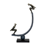 Libra Interiors Rough Cast Two Figure Balance sculpture in bronze, two crouching figures on a curved arc balanced over a sphere and plinth.