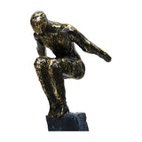 Libra Interiors Rough Cast Two Figure Balance Sculpture in bronze, close-up of a crouched stylised figure with antique gold patination on a dark plinth.