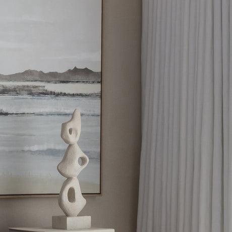 Libra Interiors Grainy Abstract Stacked Organic Sculpture in white resin on a console beside a framed coastal landscape and pale linen curtain.