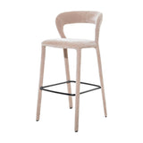 Libra Interiors Velvet Wrapped Curved Back Bar Stool in taupe, with sculptural curved back, fabric-covered tapered legs and black powder coated metal footrest.