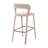 Libra Interiors Velvet Wrapped Curved Back Bar Stool in taupe, with sculptural curved back, rounded seat, fabric-covered tapered legs and black metal footrest.