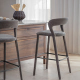 Libra Interiors Velvet Curved-Back Bar Stools in grey with low curved backrests and black powder coated footrests, set at a wooden kitchen island.
