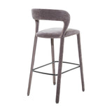 Libra Interiors Velvet Curved-Back Bar Stool in grey with a low curved backrest, upholstered legs and black powder coated steel footrest, on a white background.