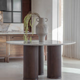 Libra Interiors Fluted Marble Top Round Dining Table in grey with three walnut fluted legs, styled with a stone vase and trailing foliage in a dining room.