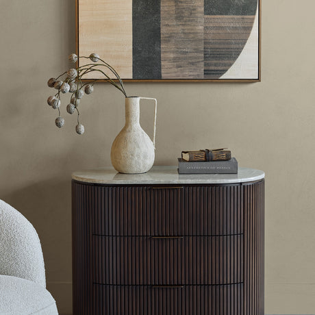 Libra Interiors Fluted Walnut Marble-Top Chest of Drawers in a bedroom, styled with a textured vase, books, and abstract wall art above.