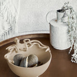 Libra Interiors Octopus Stonewash Decorative Bowl in beige aluminium, holding dried seed pods on a dark wood table beside a textured white vase.