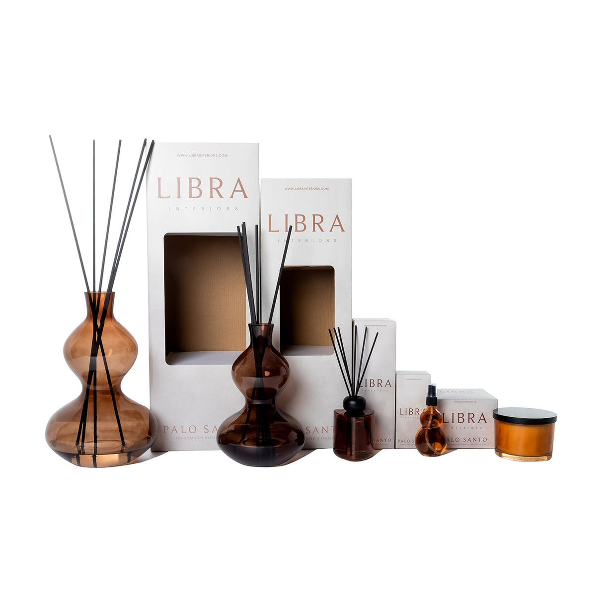 Libra Interiors Palo Santo fragrance collection with amber glass reed diffusers in two sizes, spray bottle, candle and branded boxes on a white background.