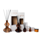 Libra Interiors Palo Santo fragrance collection with amber glass reed diffusers in two sizes, spray bottle, candle and branded boxes on a white background.