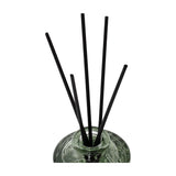 Libra Interiors Embossed Glass Reed Diffuser in green tinted glass with black reeds fanned from the neck, shown against a plain white background.