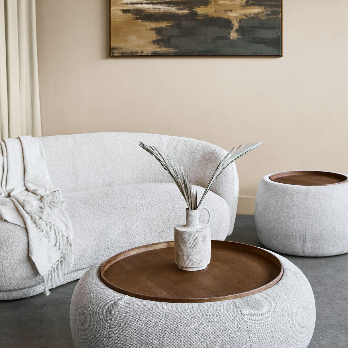 Libra Interiors Chenille Round Storage Ottoman in cream with inset walnut tray, styled with a vase in a boucle sofa living room setting.
