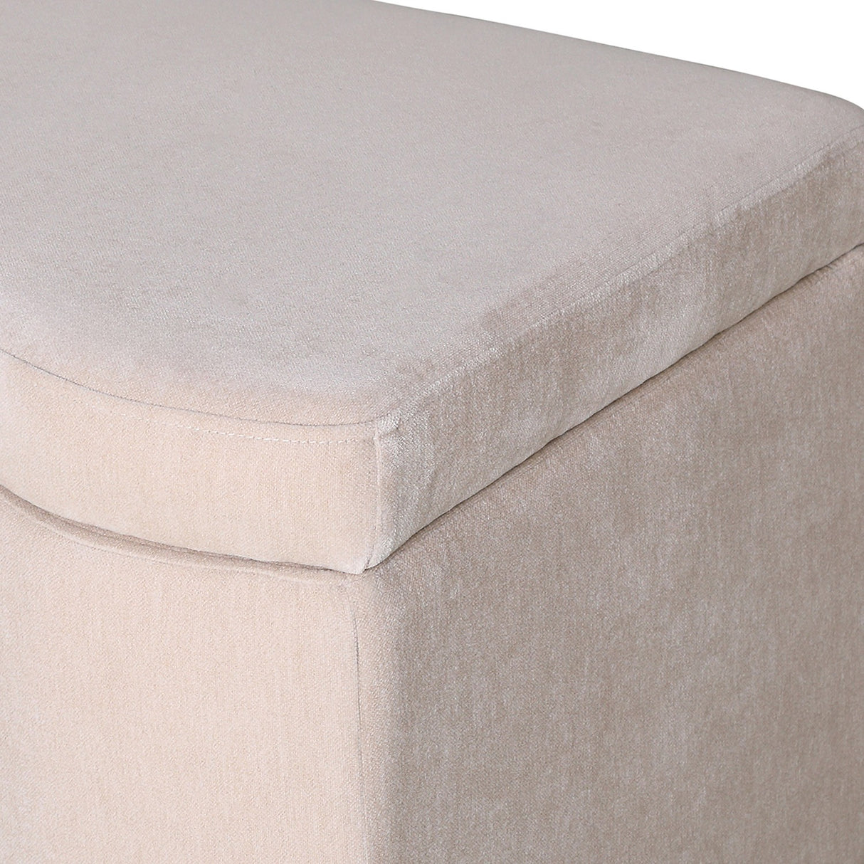 Close-up of Libra Interiors Velvet Lift-Top Storage Ottoman in cream, showing the short-pile velvet upholstery and piped seam along the lift-top lid edge.