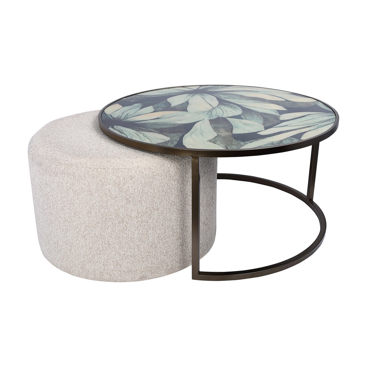 Libra Interiors Printed Glass Nesting Coffee Table in black, round leaf-print glass top on bronze-tone iron frame with oatmeal fabric pouffe tucked beneath.