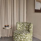 Libra Interiors Bouclé Swivel Accent Piece in ivory with olive green abstract pattern, styled in a room with linen curtains and a marble side table.