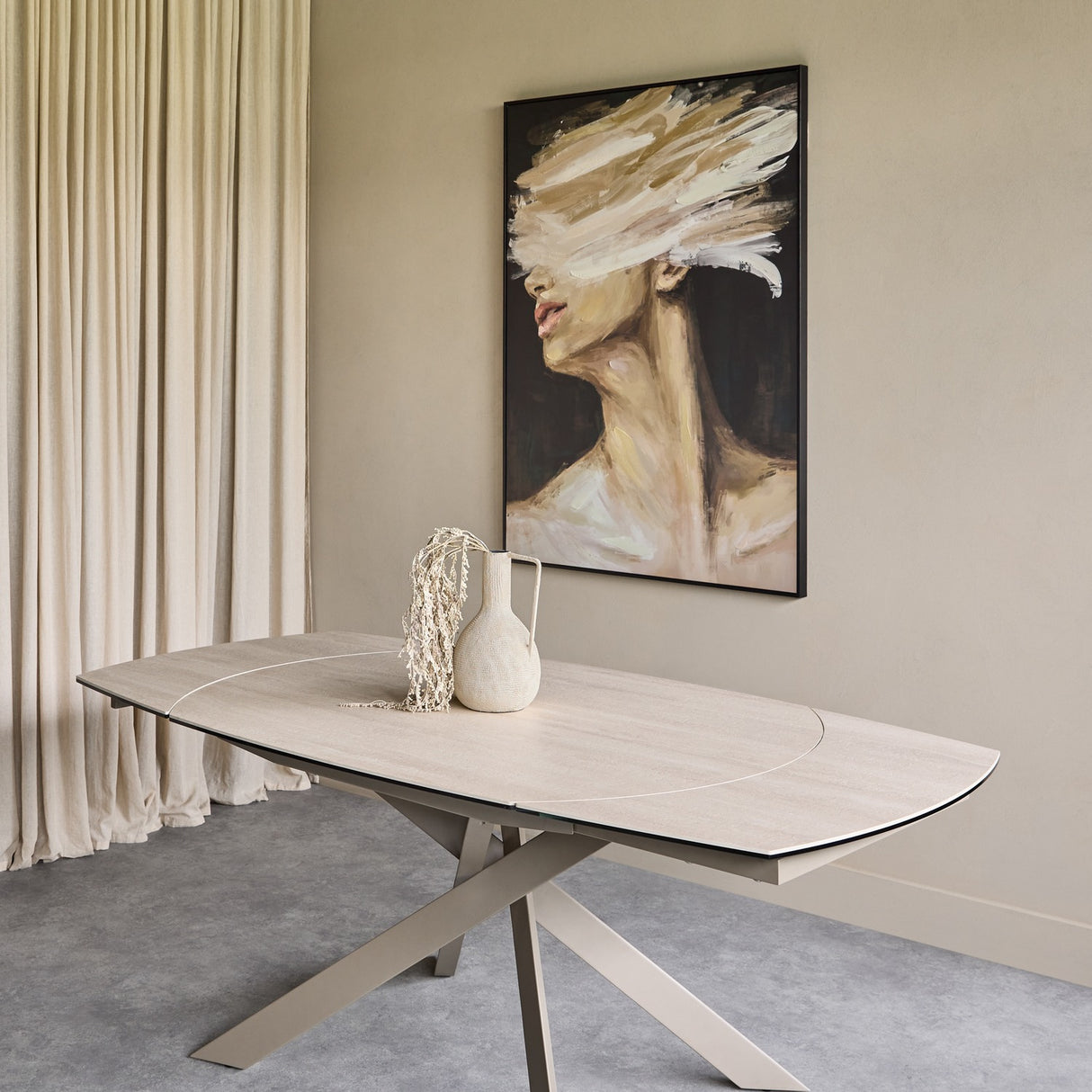 Libra Interiors extendable ceramic dining table in warm stone with brushed grey angular metal base, styled with a vase in a neutral dining room.