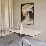 Libra Interiors extendable ceramic dining table in warm stone with brushed grey angular metal base, styled with a vase in a neutral dining room.