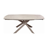 Libra Interiors extendable dining table with warm stone-effect ceramic top and sculptural brushed grey metal legs, shown extended on a plain background.
