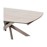 Libra Interiors extendable dining table corner detail showing warm stone-effect ceramic top and brushed grey angular intersecting metal legs.