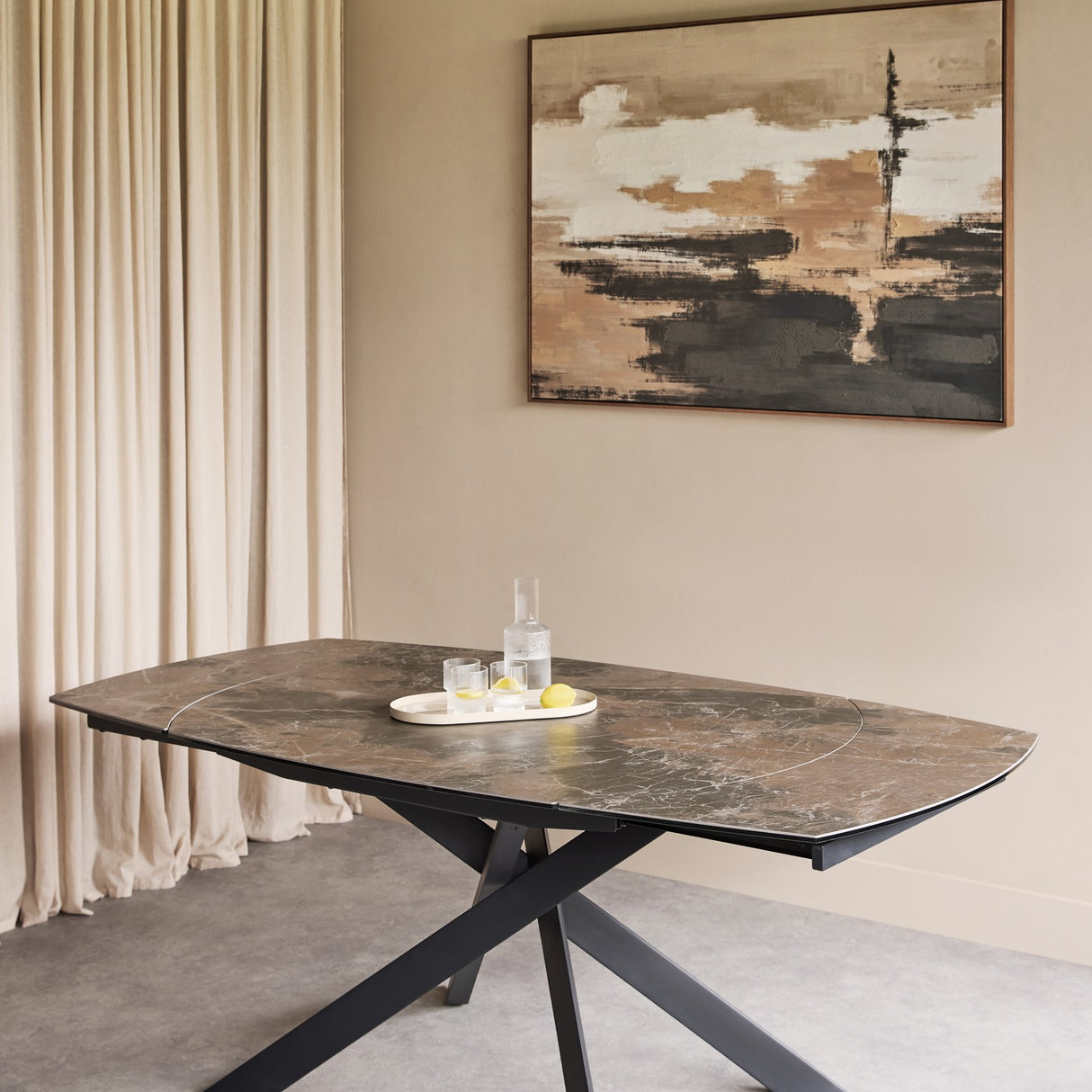 Libra Interiors extendable dining table with smoked grey ceramic stone-effect top and matt black angular metal legs, styled with a drinks tray.