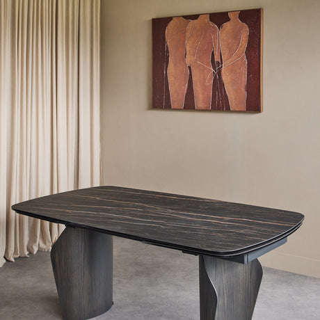 Libra Interiors extendable dining table with charcoal ceramic stone-effect top and bronze veining on dark wood-effect pedestal bases, in a neutral room.