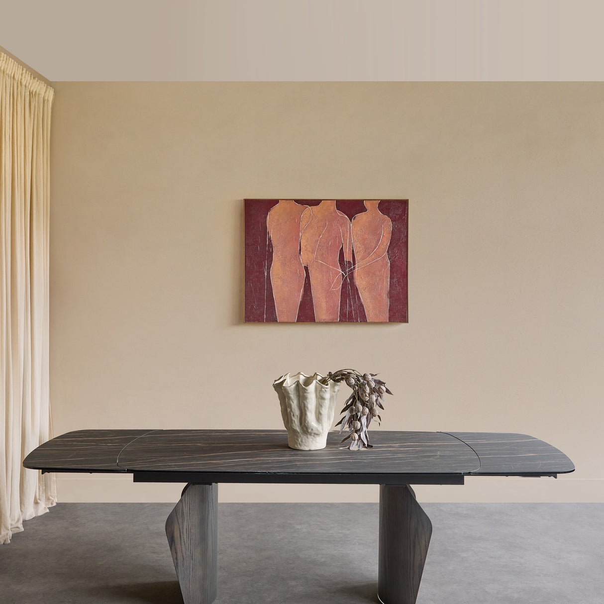 Libra Interiors Extendable Ceramic Stone Effect Dining Table in black with bronze veining and dark pedestal legs, styled with a vase beneath figurative artwork.