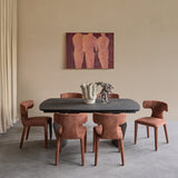 Libra Interiors extendable ceramic dining table with charcoal stone-effect top and curved pedestal base, styled with rust upholstered chairs in a dining room.