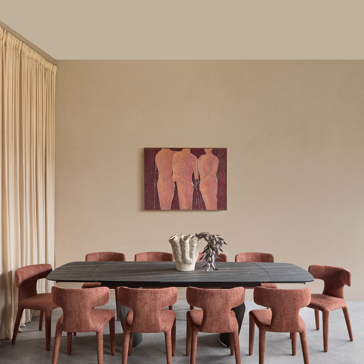 Libra Interiors extendable ceramic dining table in black with bronze veining, styled with terracotta chairs beneath figurative art in a beige dining room.