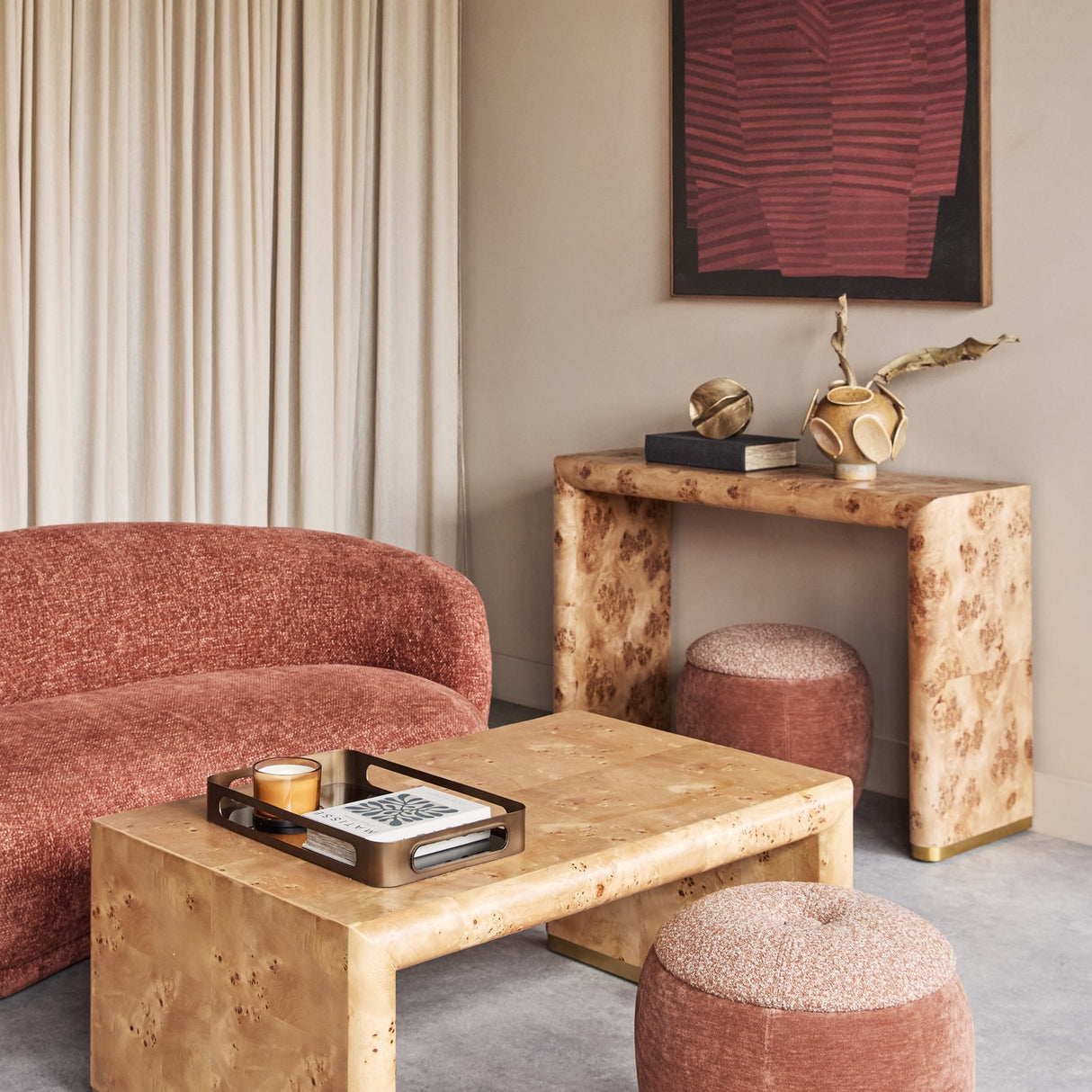 Libra Interiors Burlwood Waterfall Coffee Table in brown with brass-footed legs, styled with a tray in a living room beside a terracotta sofa and pouffes.