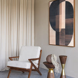 Libra Interiors Atherton mango wood armchair with angular dark timber frame and cream woven cushions, styled beside linen curtains and geometric wall art.