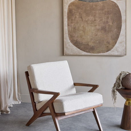 Libra Interiors Atherton mango wood armchair with angular dark-stained frame and cream woven cushions, styled beside abstract art and linen curtains.