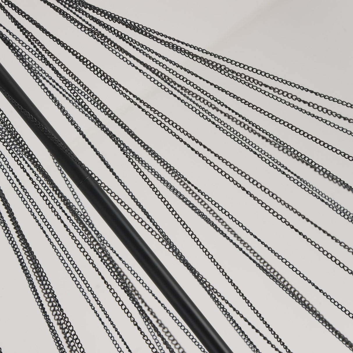 Close-up of fine black chains and a matt black drop rod from the Niori Orb 37 Light Cluster Chandelier, shown against a pale background.