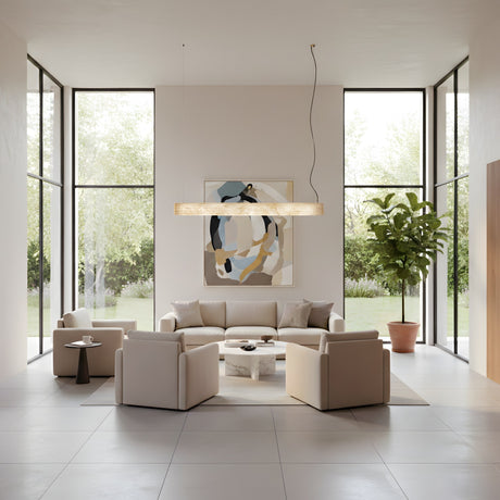 A modern living room features large windows, neutral furniture, a round coffee table, potted plant, abstract wall art, and the Zenvia LED Alabaster Suspension Light – Soft White overlooking a lush outdoor garden.