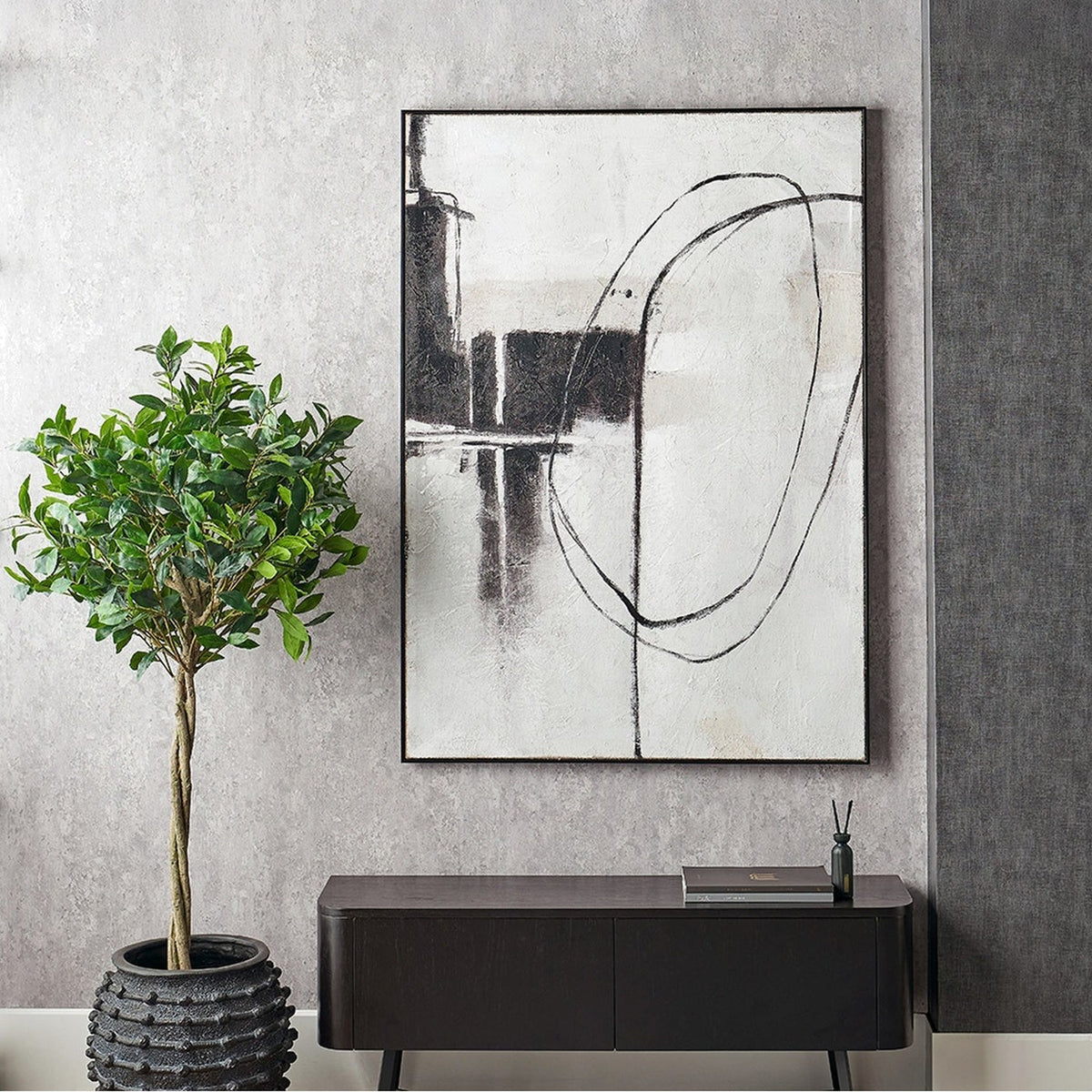 Monochrome Abstract Canvas with black frame, 100 x 140cm, featuring bold black brushstroke shapes on a white ground, hung above a dark sideboard beside a potted plant.