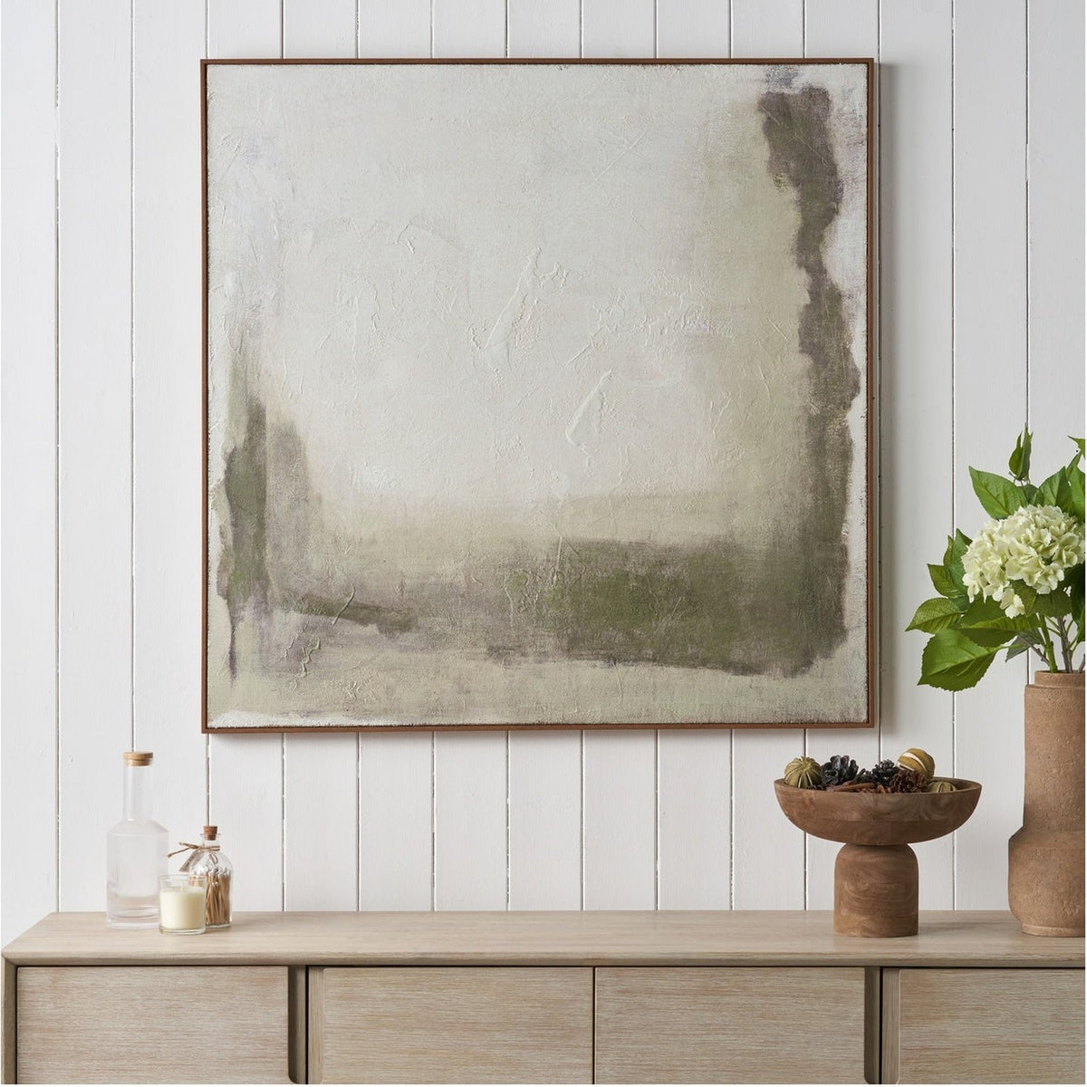 Square abstract hessian canvas wall art in green and natural tones with an oak effect frame, displayed above a wooden sideboard.