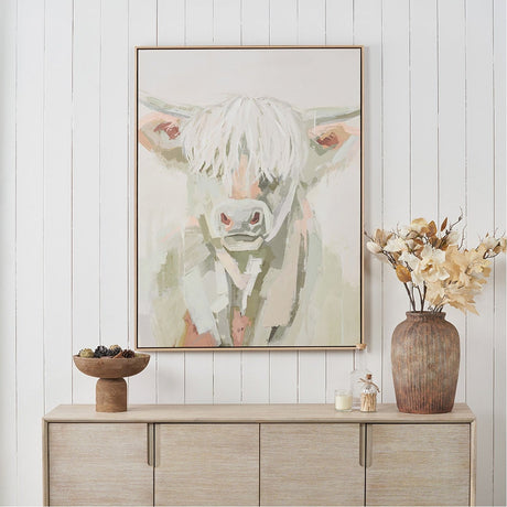 Sage & Naturals Highland Cow Canvas with Natural Frame, 90 x 120cm, hung above a wooden sideboard styled with a vase, candle, and pinecone bowl.